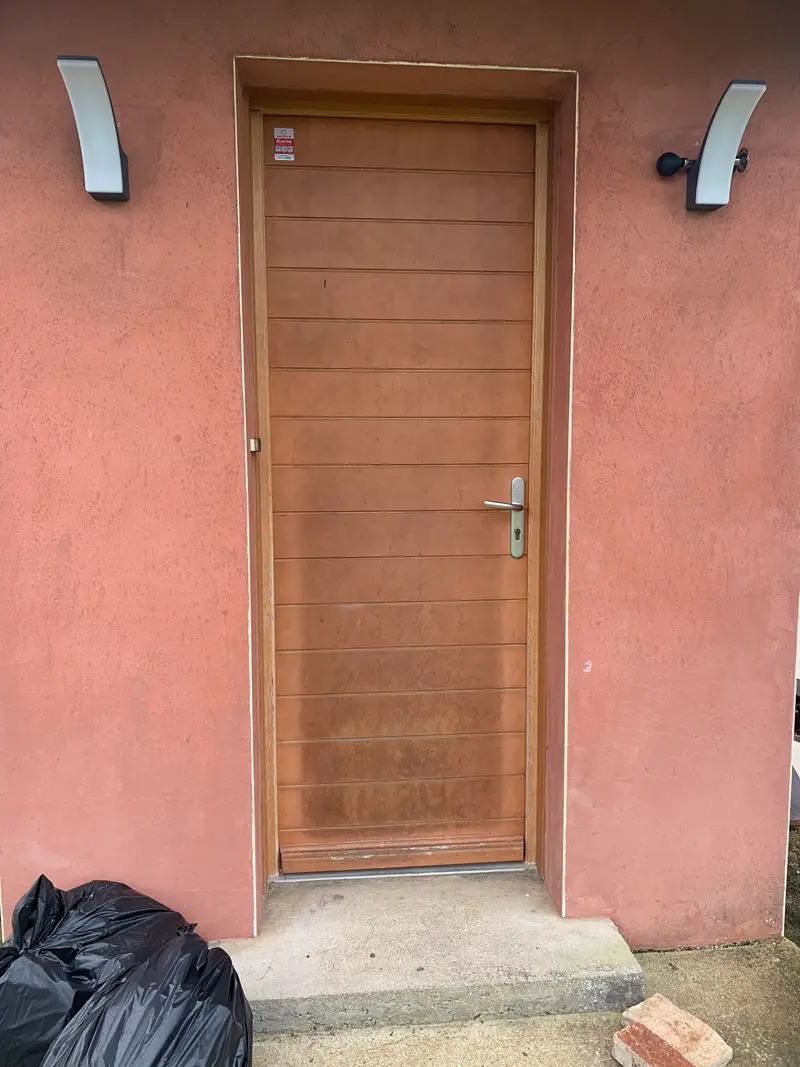 Avant : ancienne porte d'entrée bois vieillissante sur façade rose