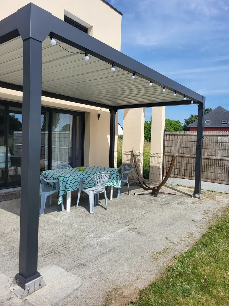 Pergola aluminium avec guirlande lumineuse et coin repas extérieur