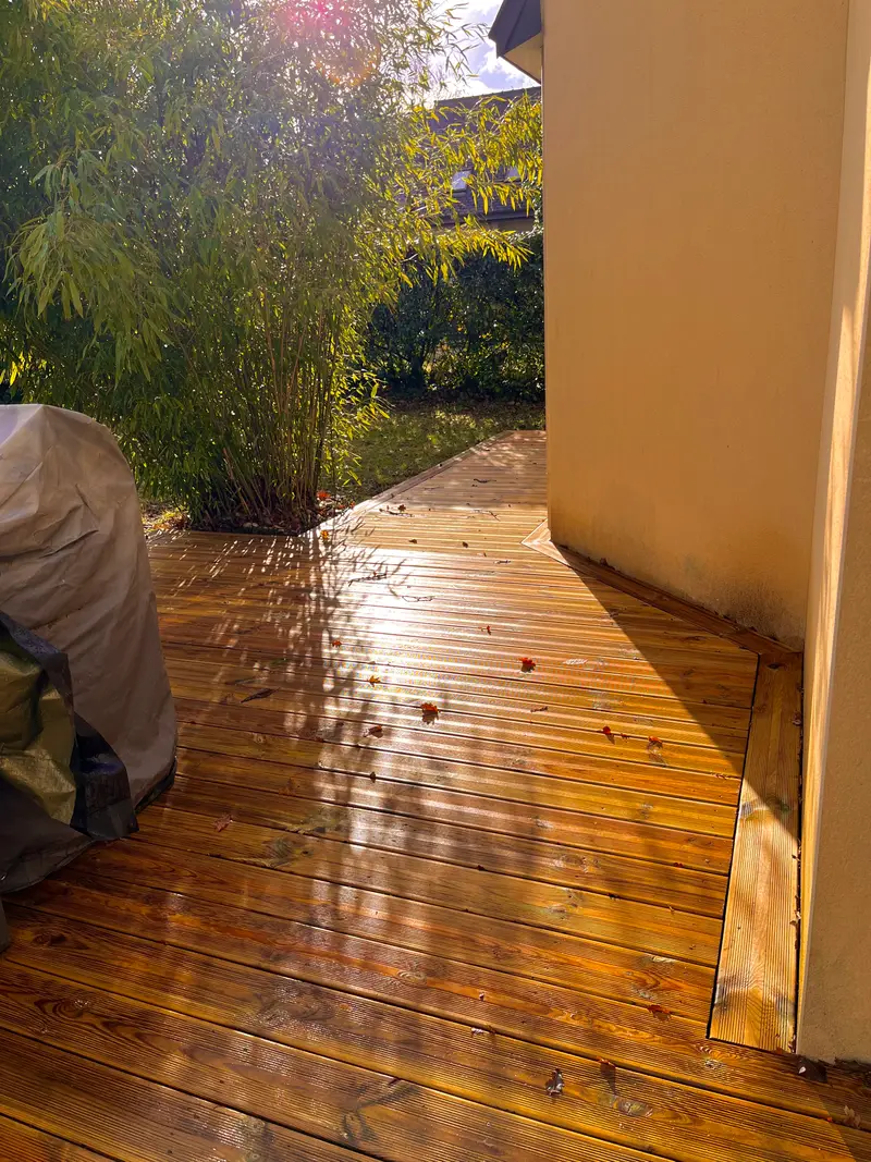 Terrasse en bois clair à lames rainurées le long d'une façade