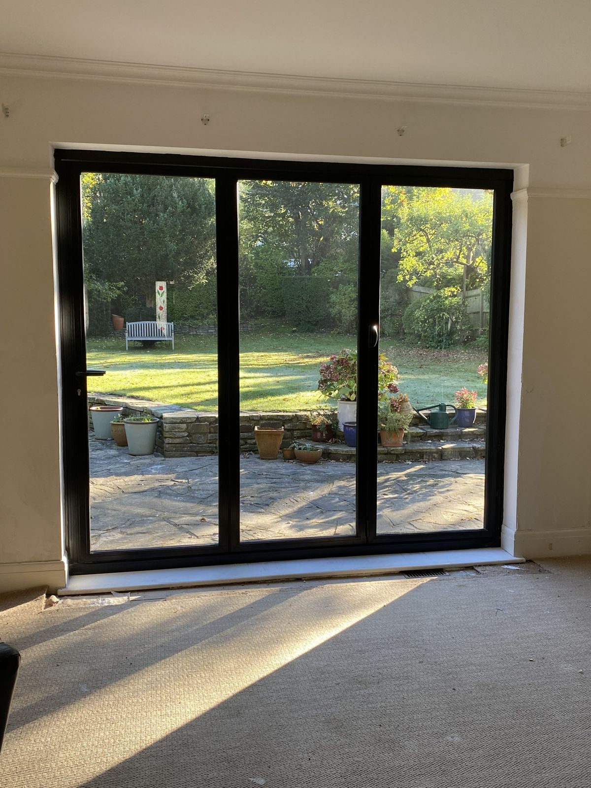 Baie vitrée coulissante aluminium donnant sur un jardin