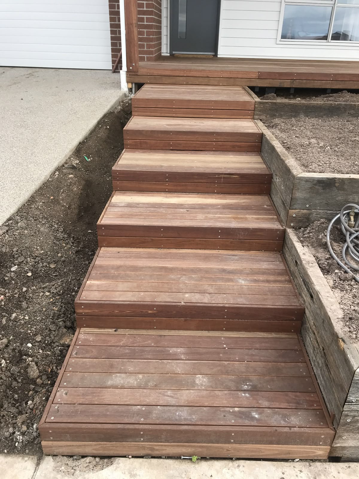 Escalier extérieur en bois en cours de pose, menant à une terrasse surélevée