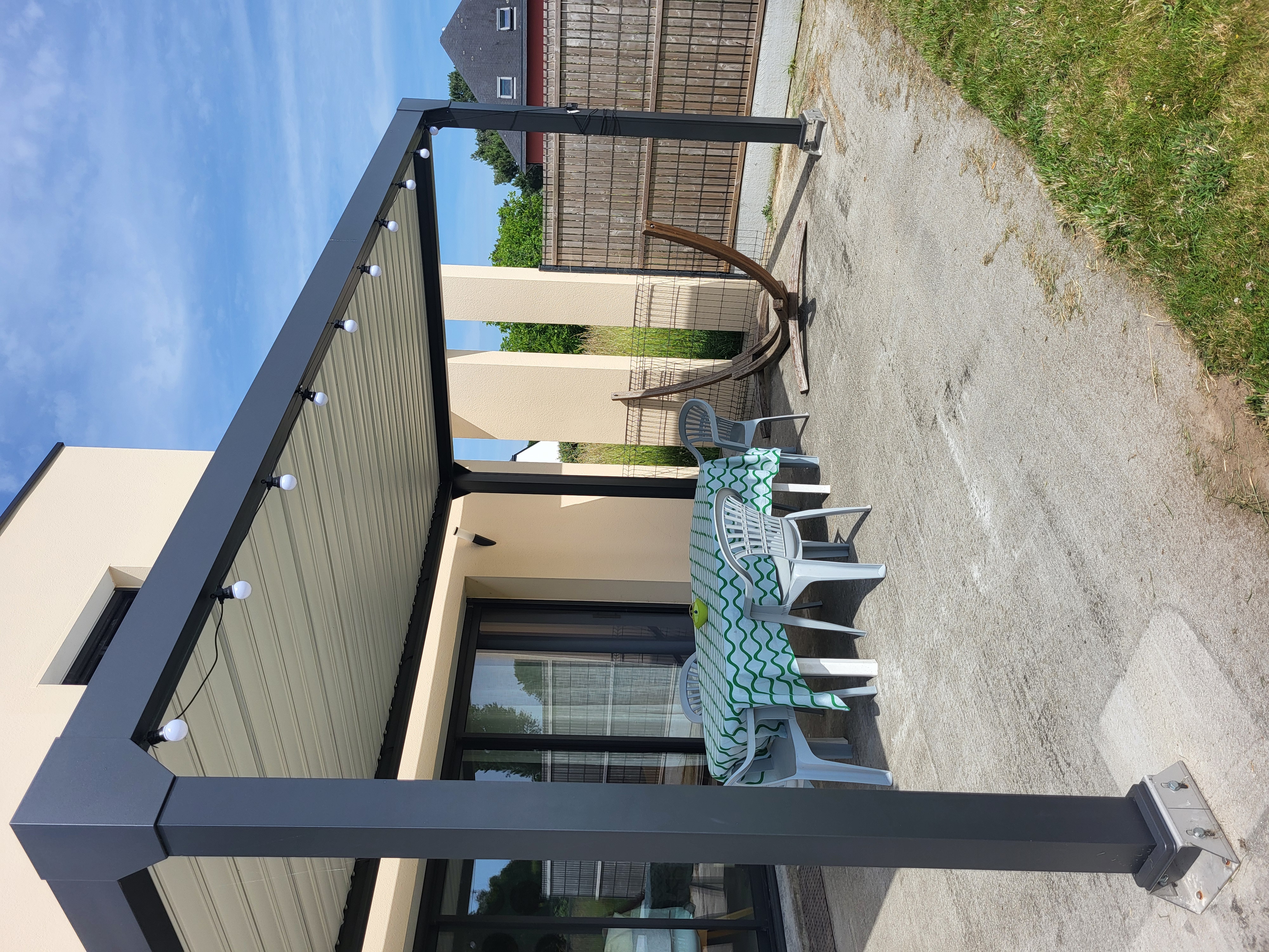 Pergola aluminium avec guirlande lumineuse et coin repas extérieur